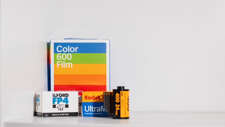 A collection of photographic film and camera film packaging arranged on a white surface against a plain white background. The assortment includes a large box of color film labeled 'Color 600 Film' wit